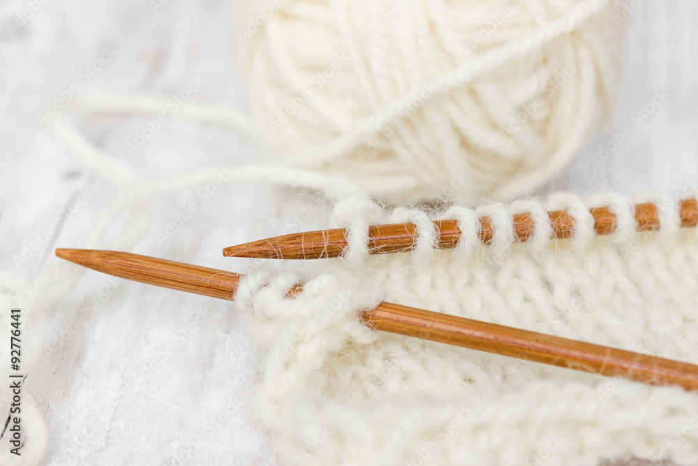 Sample of knitting from woolen yarn white color on wooden knitti Sample of knitting from woolen yarn white color on wooden knitti