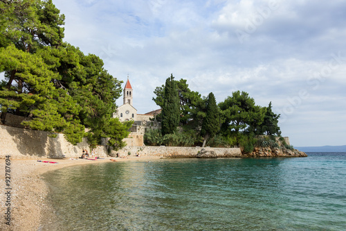 Small and tranquil beach in Bol, Croatia. Small church of St. Ivan and Teodor in the background. photo