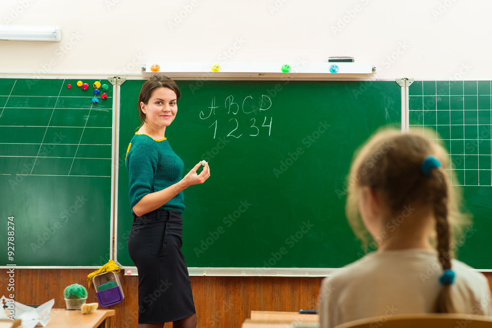 teacher in the classroom writing on the chalkboard teacher in the classroom writing on the chalkboard