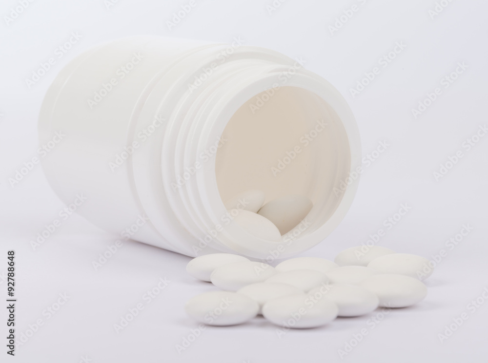 Scattered pills from open white bottle Scattered pills from open white bottle