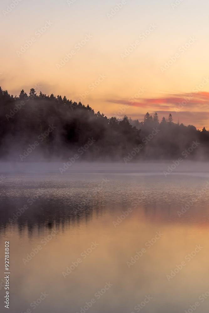 Fototapeta premium colorful fall sunrise by a lake with mist over the water