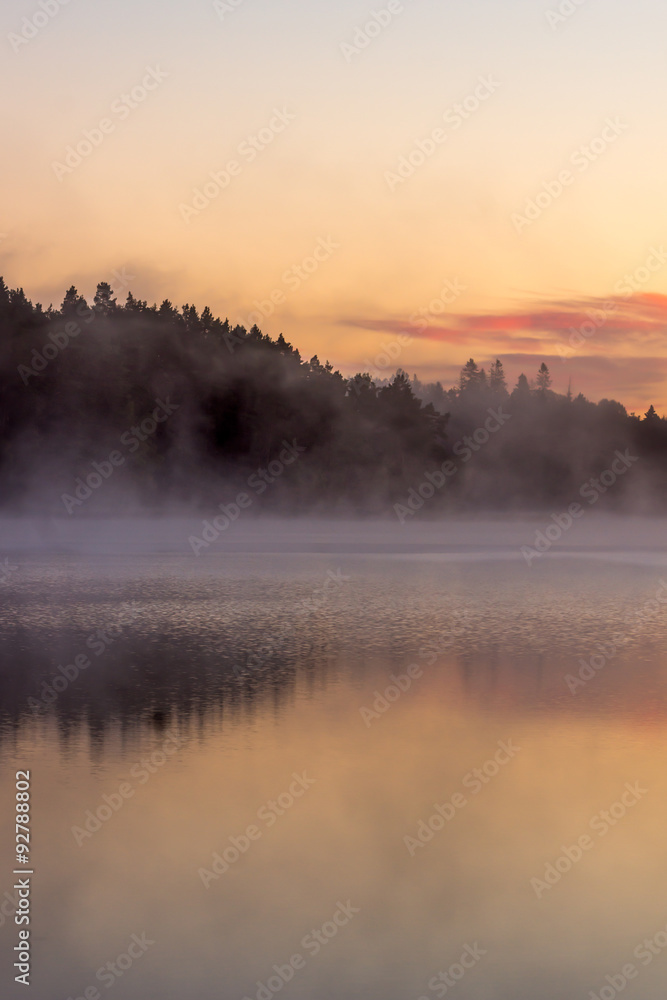 colorful fall sunrise by a lake with mist over the water