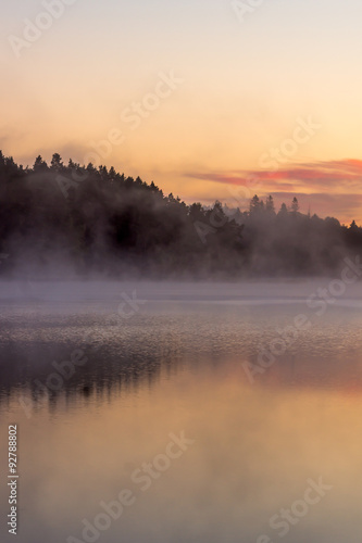 colorful fall sunrise by a lake with mist over the water