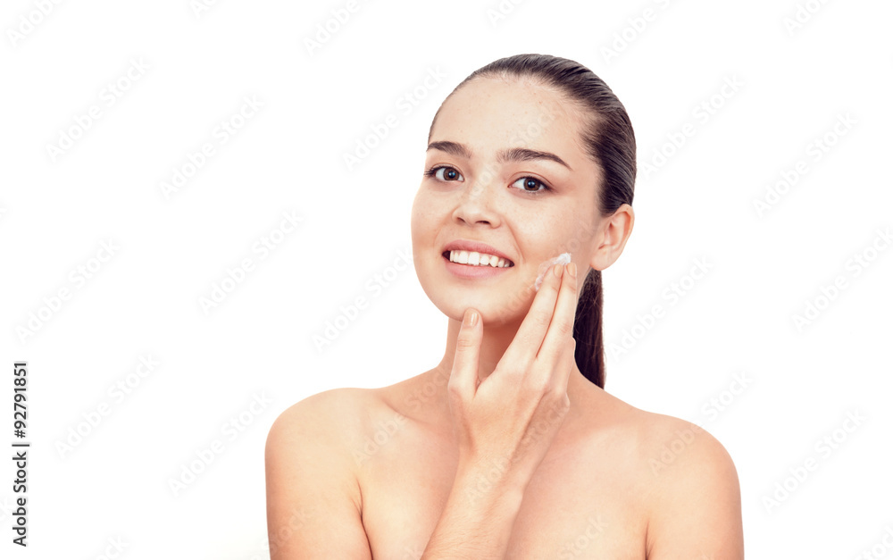 Young beautiful Asian applies a cream into the face. Hair collected. She looks at the camera. Naked shoulders. Nude manicure. Freckles. Young beautiful Asian applies a cream into the face. Hair collected. She looks at the camera. Naked shoulders. Nude manicure. Freckles.