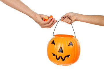 Male hand putting candies in pumpkin candy basket on white backg