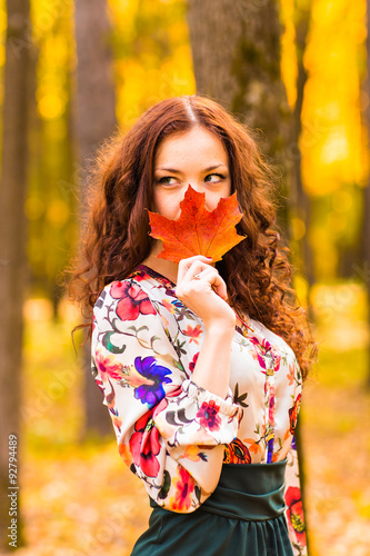 Young woman with autumn leaves in hand 