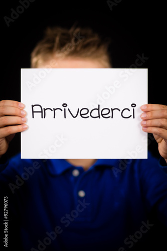 Child holding sign with Italian word Arrivederci - See you later