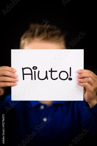 Child holding sign with Italian word Aiuto - Help