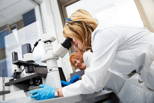 Photo of real female scientists looking into a microscope