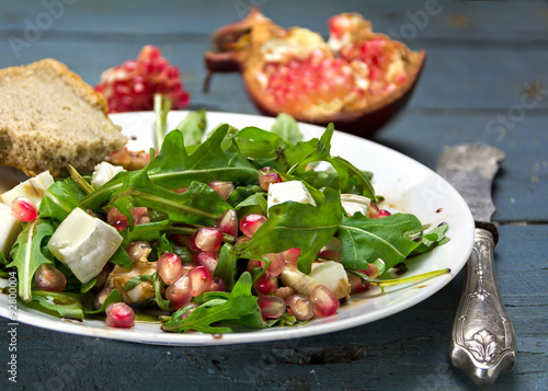 rocket salad with  feta cheese and pomegranate on an rustic wood © Maren Winter