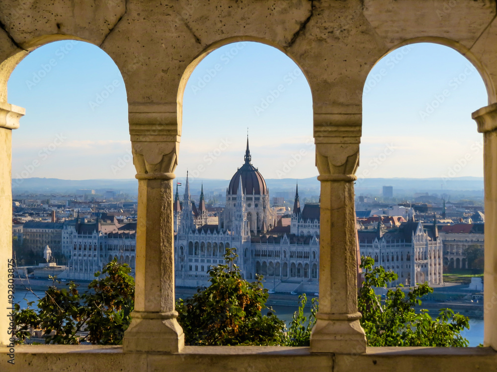 Fototapeta premium Budynek parlamentu, miasto Budapeszt, Węgry - widziane przez łuki Baszty Rybackiej Zamku Królewskiego