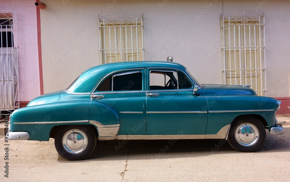 Classic American car as taxi parked in the street in front of old buildings in historic Trinidad, Cuba. 