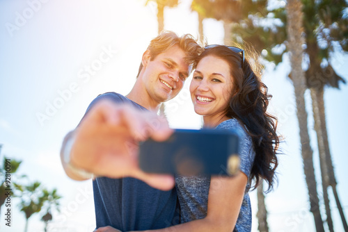 happy couple in the sun taking romantic selfie together