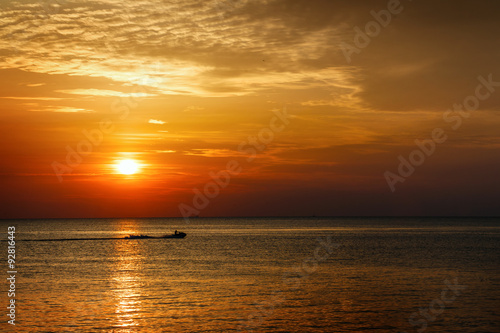 Silhouette of a man on a jet ski in the sea at sunset. © Vagengeim