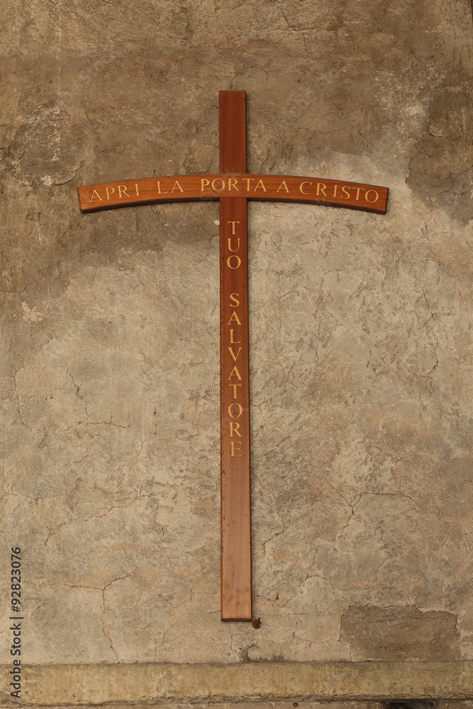 Cross on a old stucco wall with inscription on italian