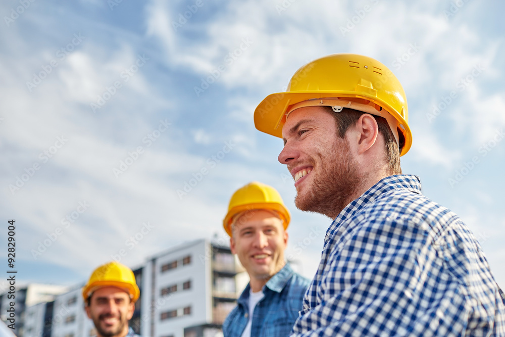 group of smiling builders in hardhats outdoors group of smiling builders in hardhats outdoors