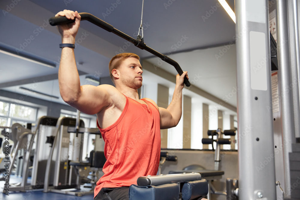 man flexing muscles on cable machine gym man flexing muscles on cable machine gym