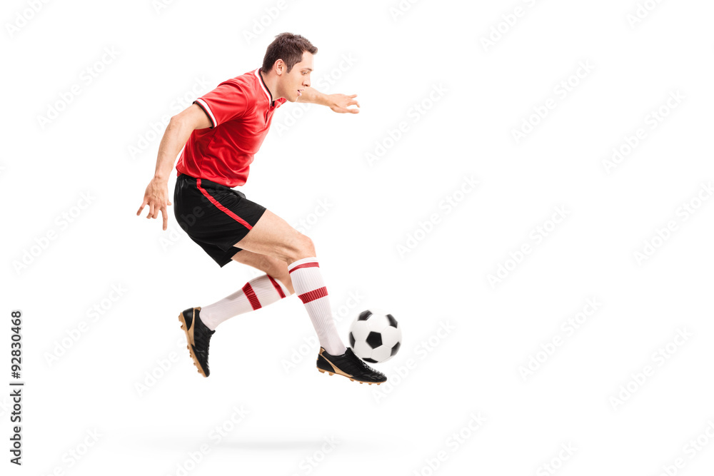 Young athlete jumping and kicking a football