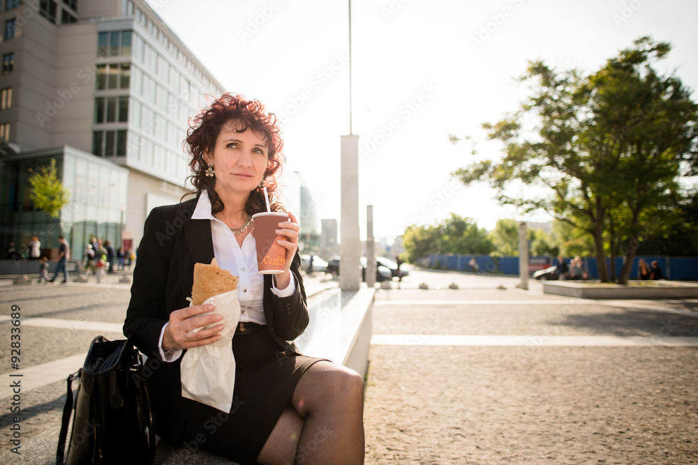 Fototapeta premium Quick lunch - business woman eating in street