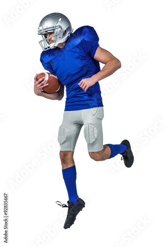 American football player holding ball in mid-air