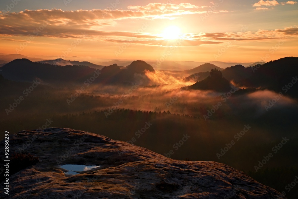 View over wet sandstone cliff into  heavy misty valley in Saxony Switzerland. Peaks of hills increased fromdense  fog