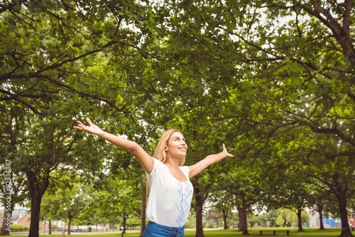 Beautiful woman with arms raised in park
