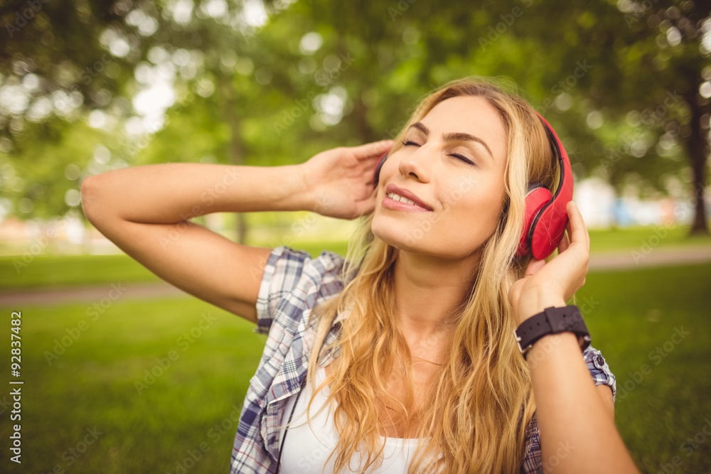 Smiling woman enjoying music with eyes closed at park