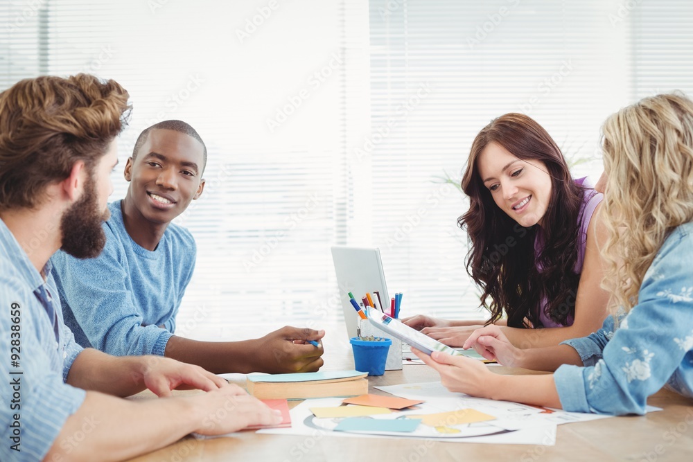 Smiling business people discussing while working at desk Smiling business people discussing while working at desk