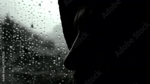 Closeup of man in darkness in front of rain thinking feeling lonely