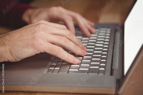 Cropped hand of man working on laptop