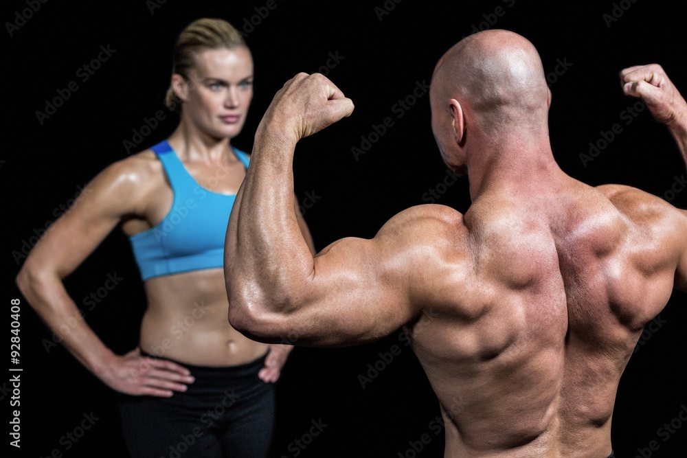Bald muscular man flexing muscles in front of trainer Bald muscular man flexing muscles in front of trainer