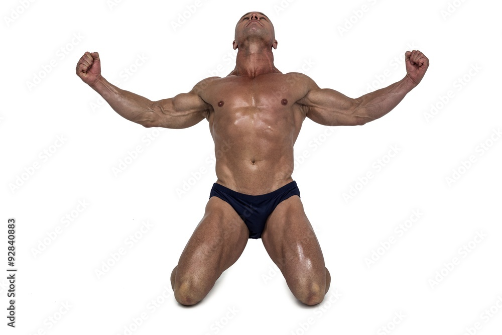 Muscular man kneeling down with arms outstretched Muscular man kneeling down with arms outstretched