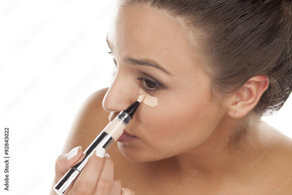 young woman apply concealer under the eye