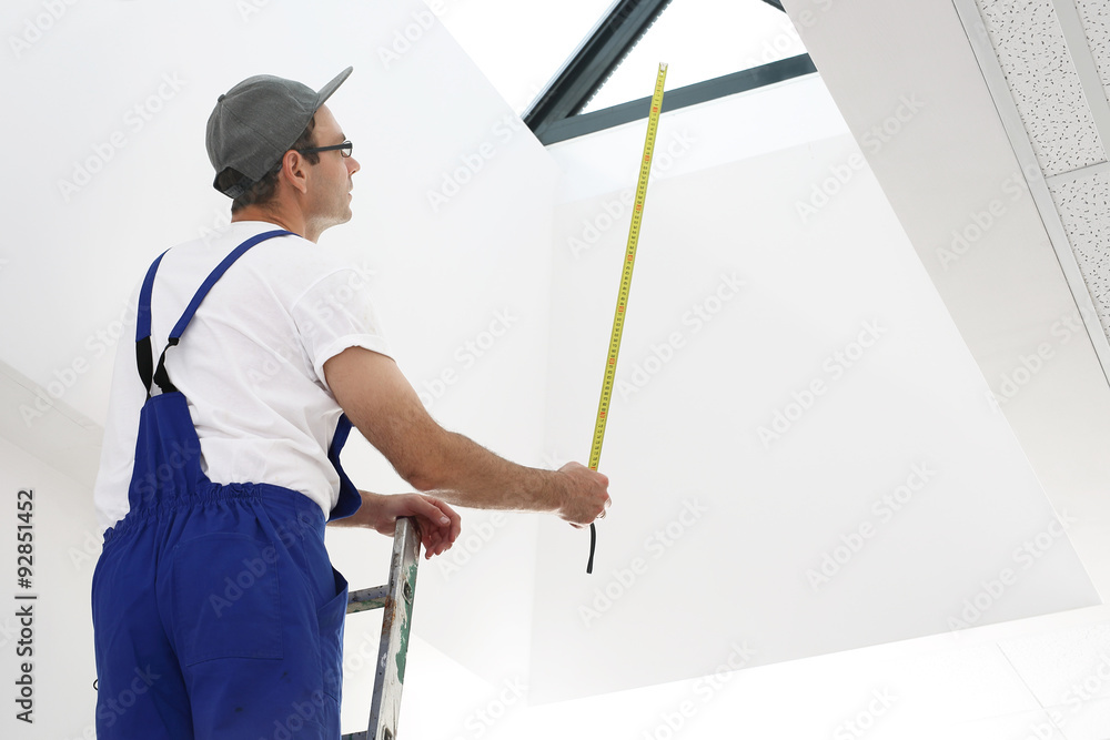 Mężczyzna w stroju roboczym pracuje przy montażu okien dachowych - obrazy, fototapety, plakaty 