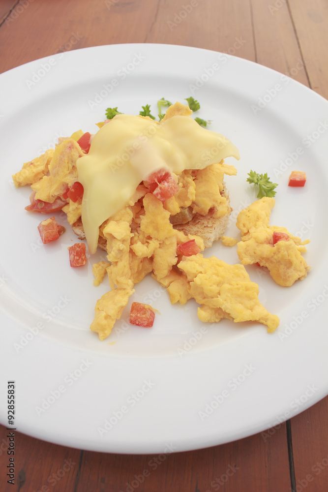Scrambled egg with cheese and pancake in white dish on wooden table Scrambled egg with cheese and pancake in white dish on wooden table