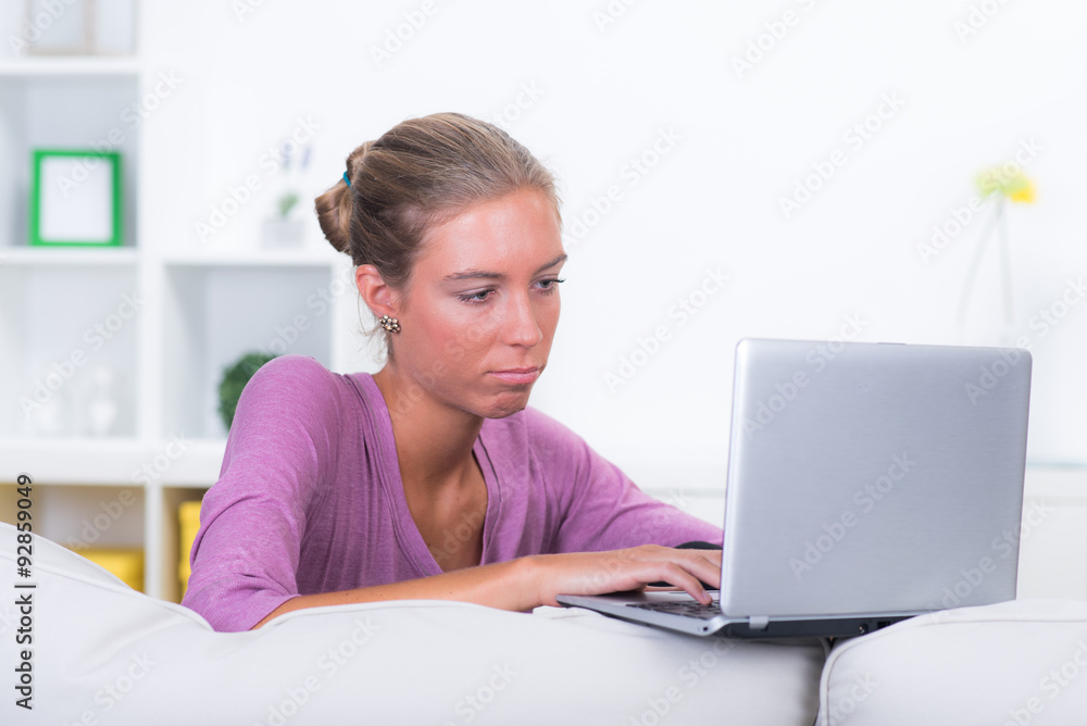 Unzufriedene Studentin mit Notebook im Wohnzimmer Unzufriedene Studentin mit Notebook im Wohnzimmer