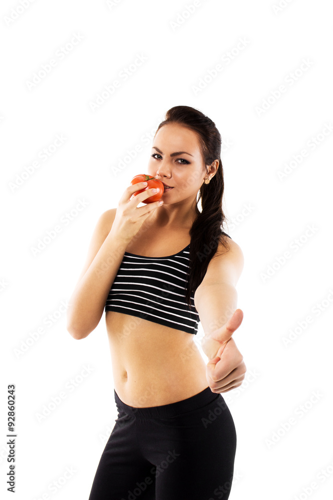 Slim girl wearing training suit tasting a tomato Slim girl wearing training suit tasting a tomato