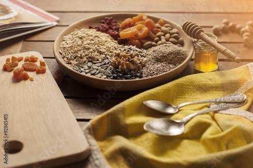 Healthy breakfast. Granola with nuts, seeds, honey, frozen raspberries pumpkin in a wooden biwk on wooden table © sergiubirca