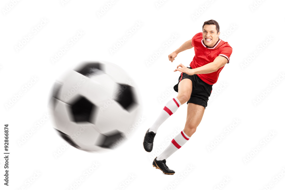 Young football player kicking a ball hard