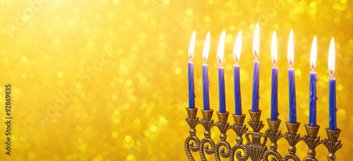 Jewish holiday Hanukkah website banner design with menorah and candles over golden bokeh