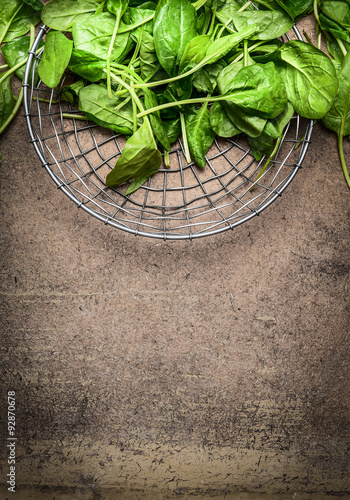 Fresh spinach leaves in a metal basket on rustic wooden background