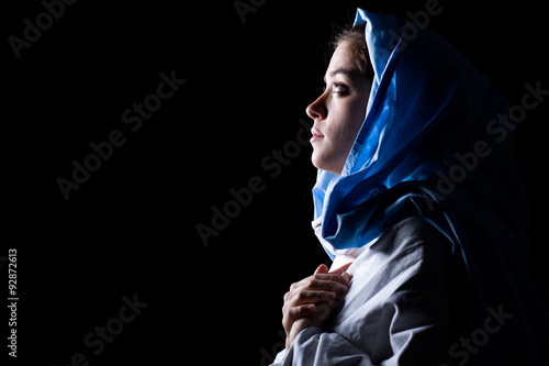 Virgin Mary with Blue Veil Praying on Black Background photo