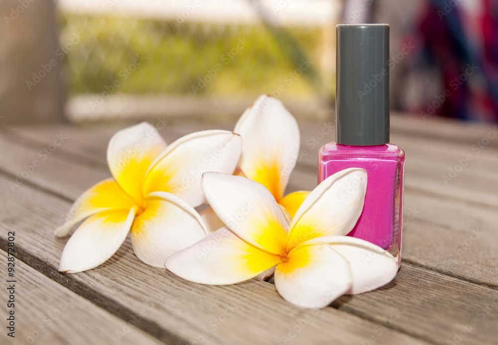 Fuchsia nail polish in the bottle and flowers on the woody background Fuchsia nail polish in the bottle and flowers on the woody background
