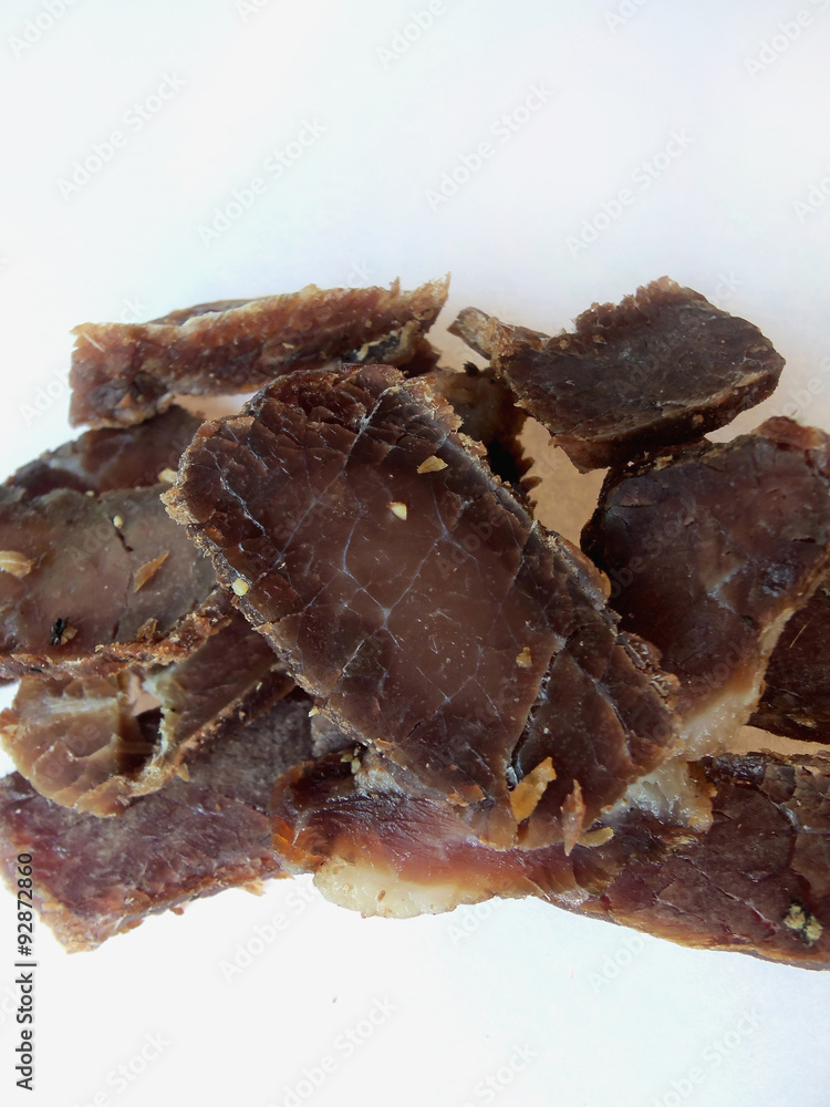 Biltong snack piled up on white paper Biltong snack piled up on white paper