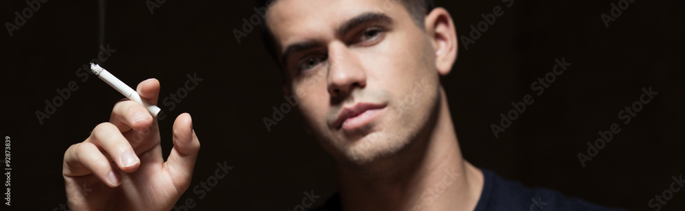 Obraz premium Young smoker holding a cigarette