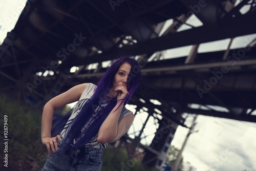 Outdoor fashion lifestyle portrait of pretty young girl, wearing in hipster swag grunge style with violet hair urban background
