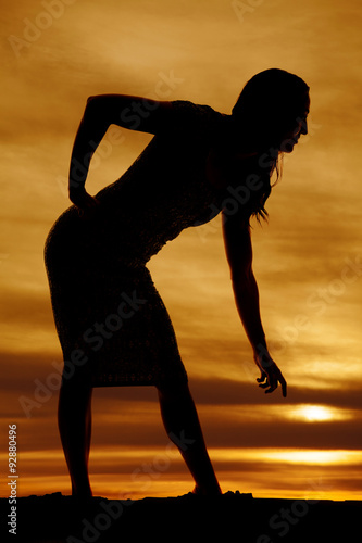 silhouette of a woman in tight dress bend down