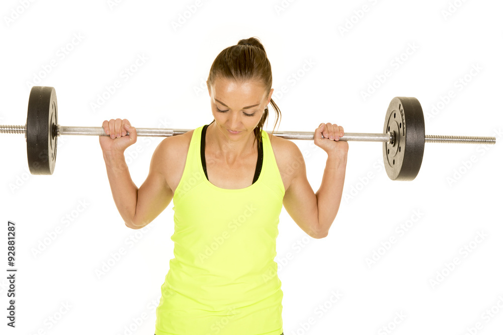 Obraz premium woman green tank top fitness barbell on shoulders look down