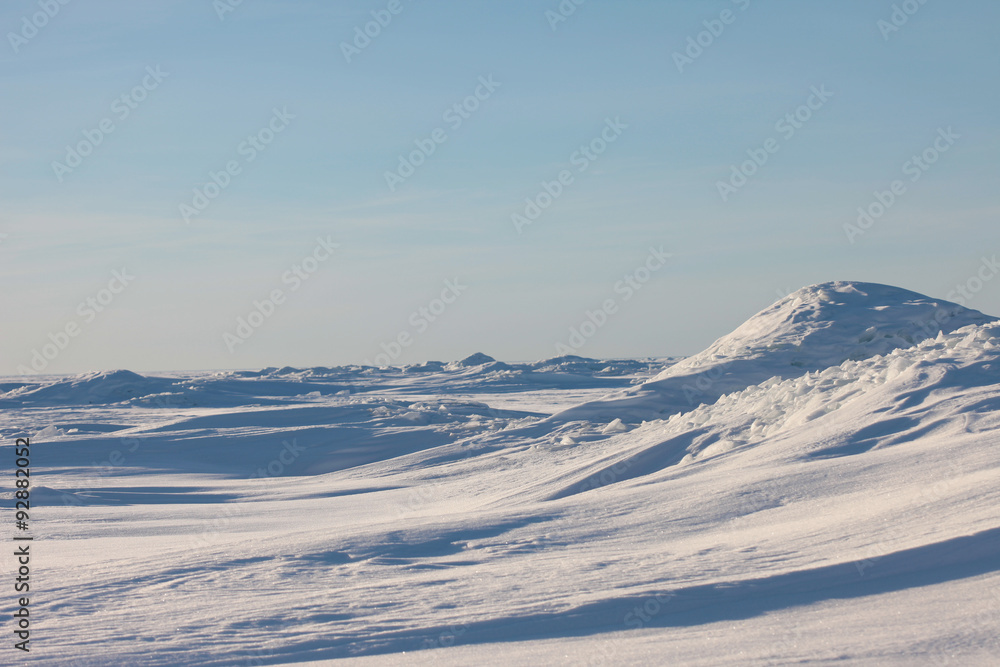Snow desert and blue winter sky. Mountains on the horizon