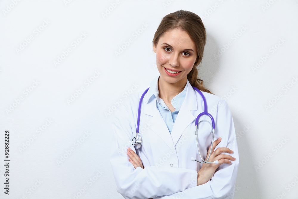Friendly smiling young female doctor, standing near wall Friendly smiling young female doctor, standing near wall